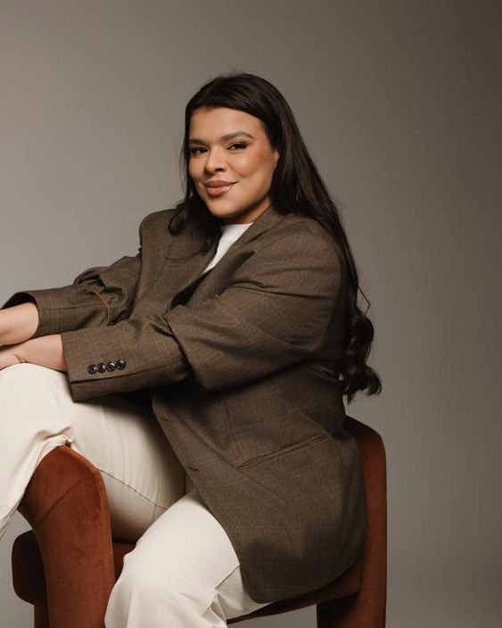 Dra. Mariani Amorim sorrindo, sentada em poltrona, retrato da biomédica da Vitamar Clinic